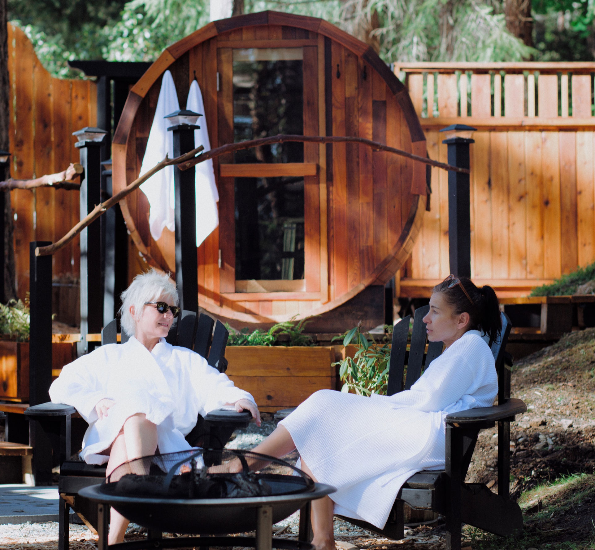 Two guests relaxing in robes by the fire pit