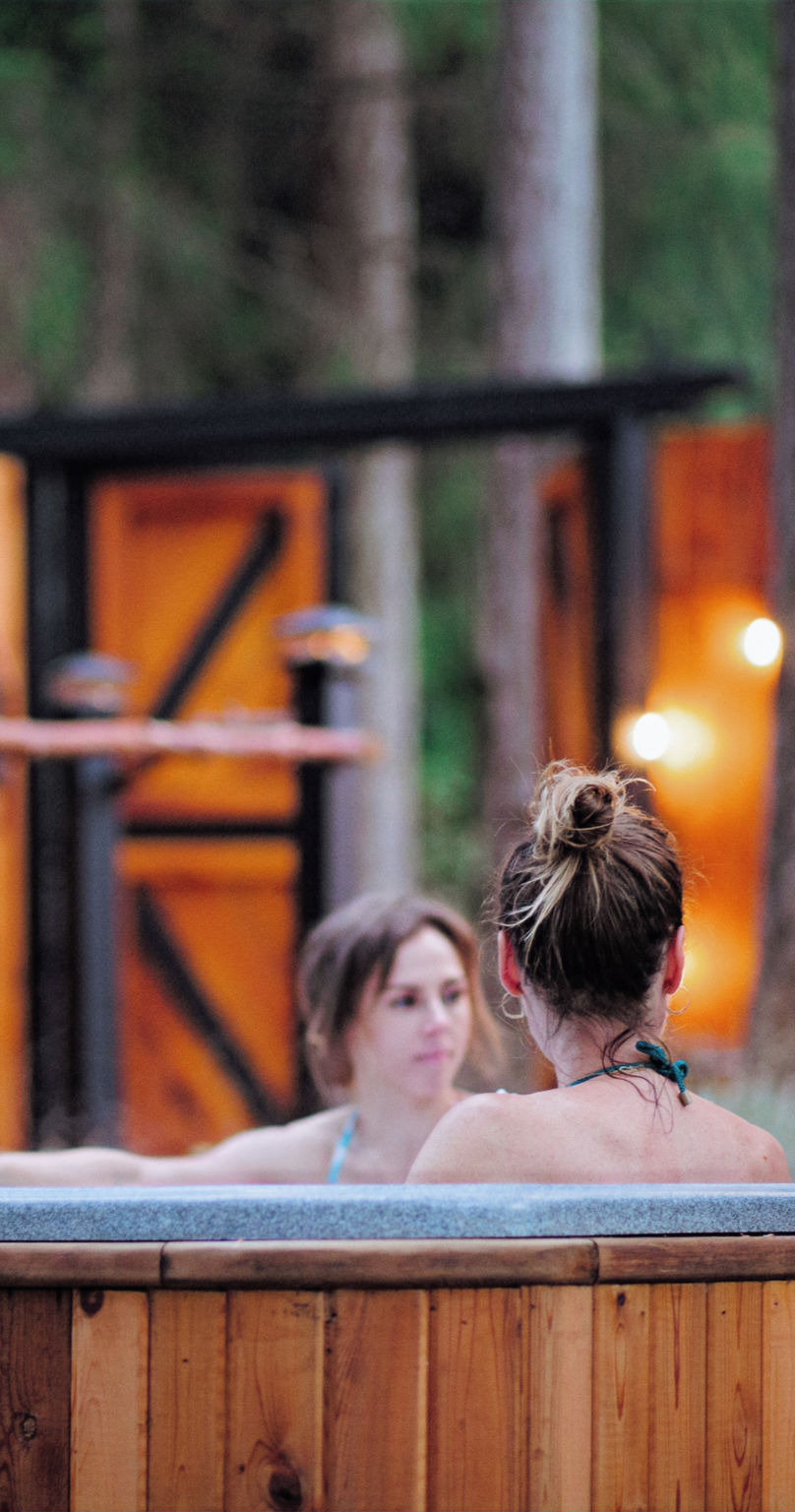 Guests in the cedar hot tub at dusk